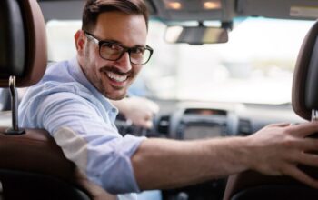 Ein lächelnder Fahrlehrer im Auto schaut zurück – Chancen durch Weiterbildung in der Fahrschulbranche.