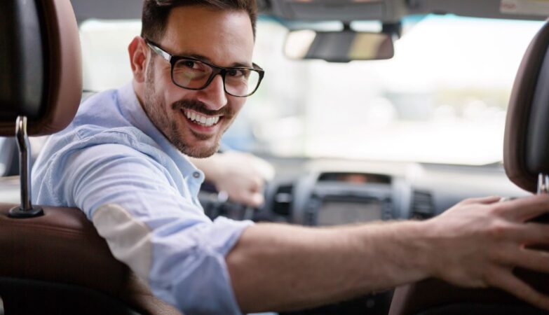 Ein lächelnder Fahrlehrer im Auto schaut zurück – Chancen durch Weiterbildung in der Fahrschulbranche.